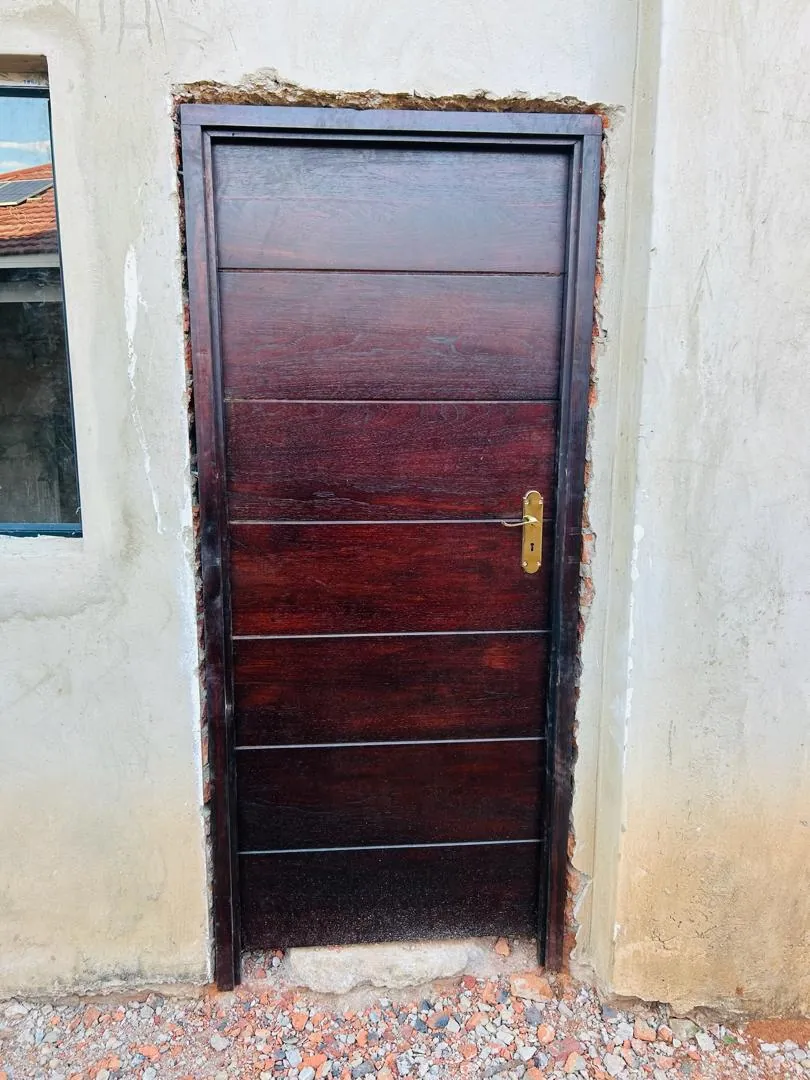 Dark timber door with horizontal panels and a brass handle in a new frame